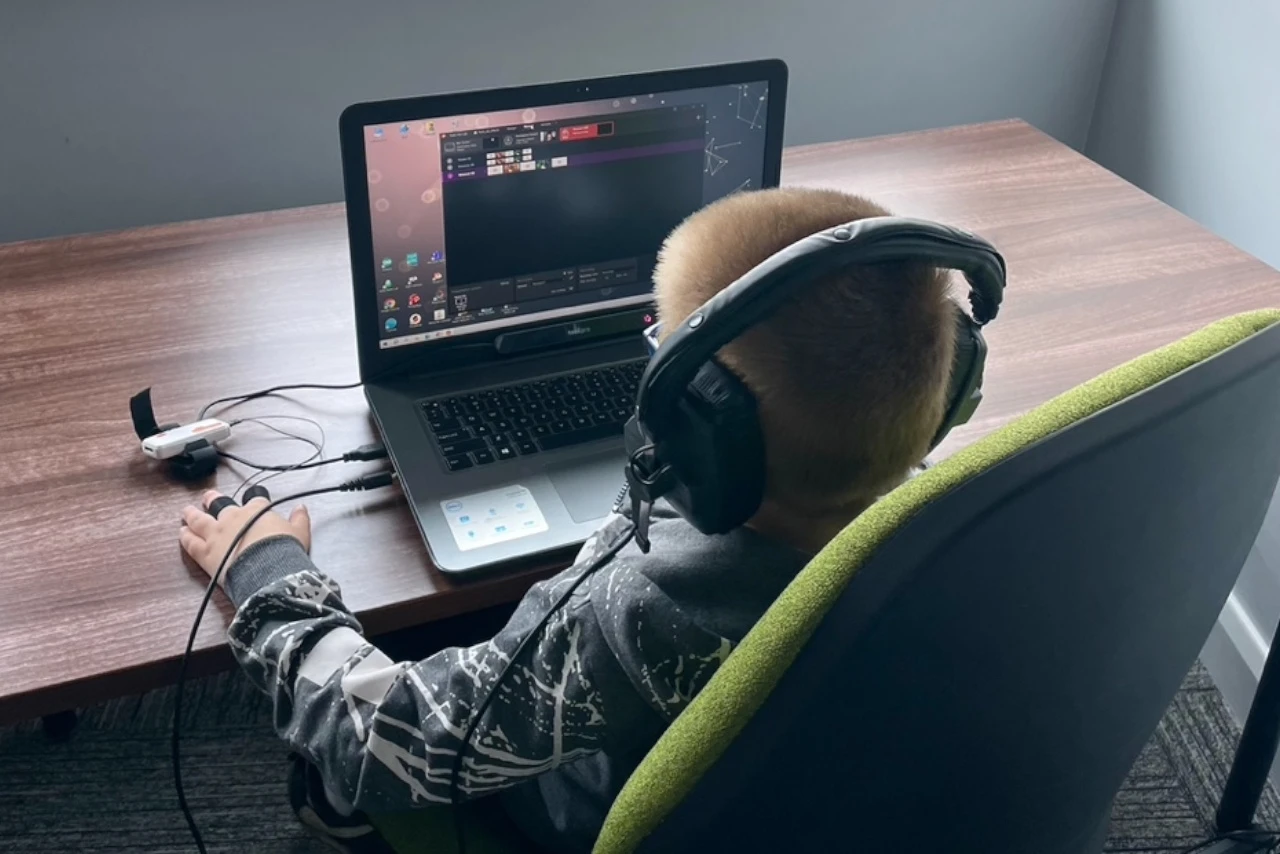 A child in front of a computer with headphones.