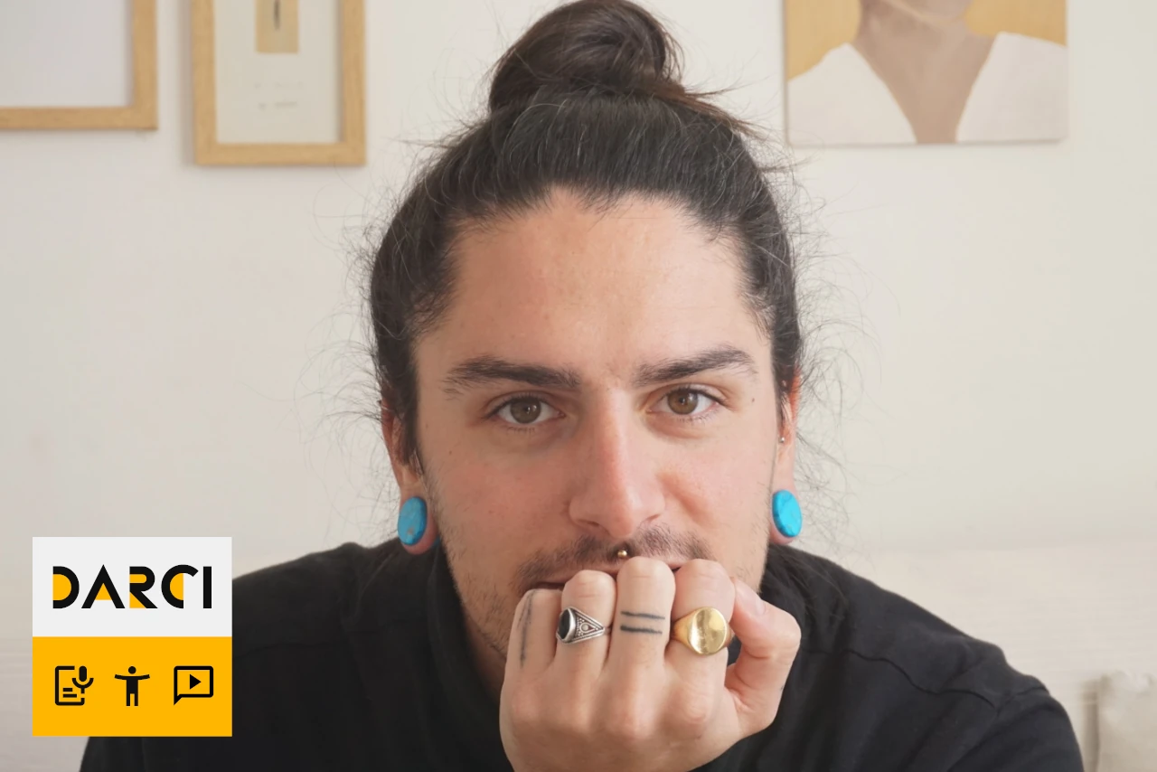 Headshot of Gonzalo Iturregui Gallardo wearing a black shirt and blue earrings. DARCI logo in bottom left corner.