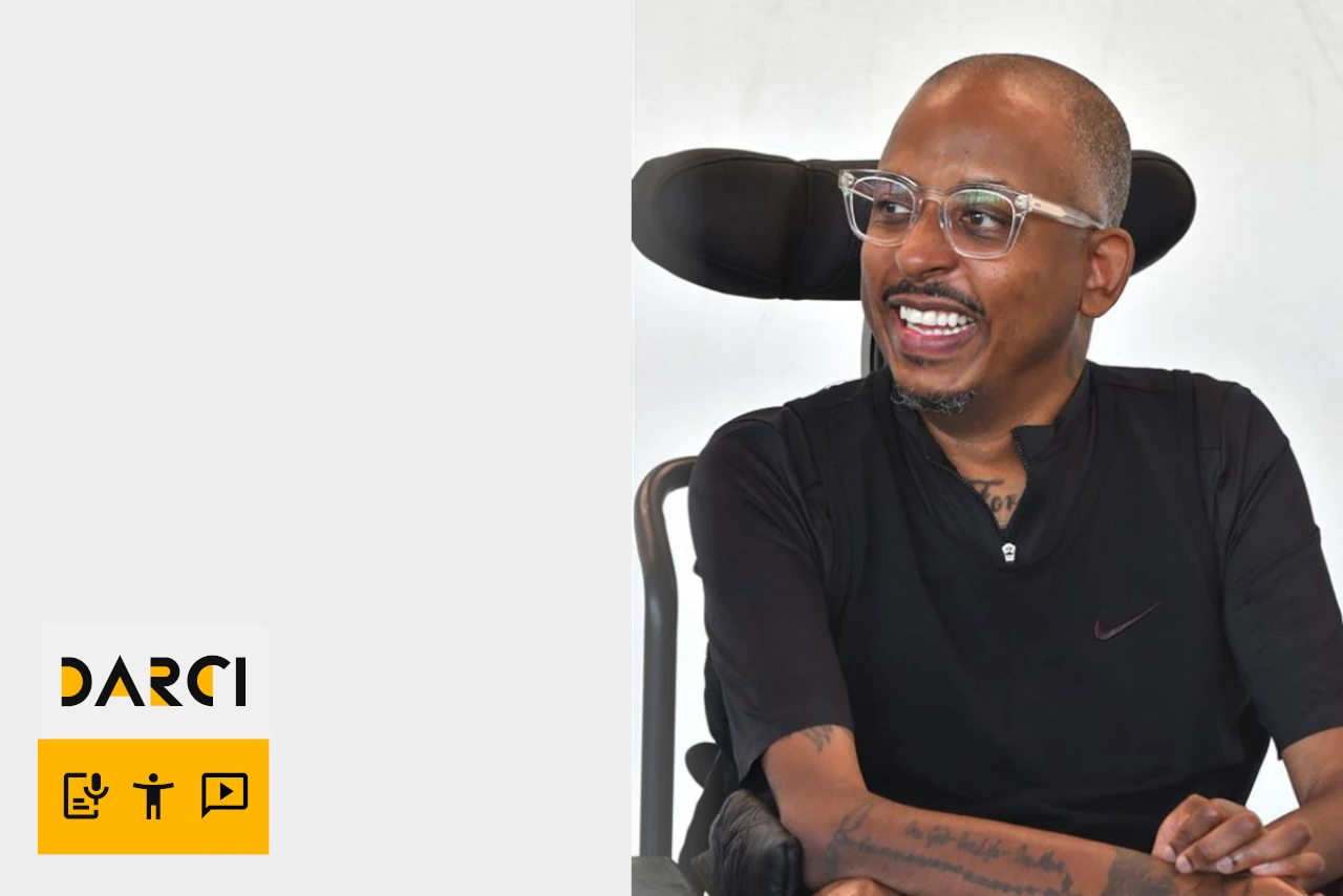 Samuel sits in his chair smiling.