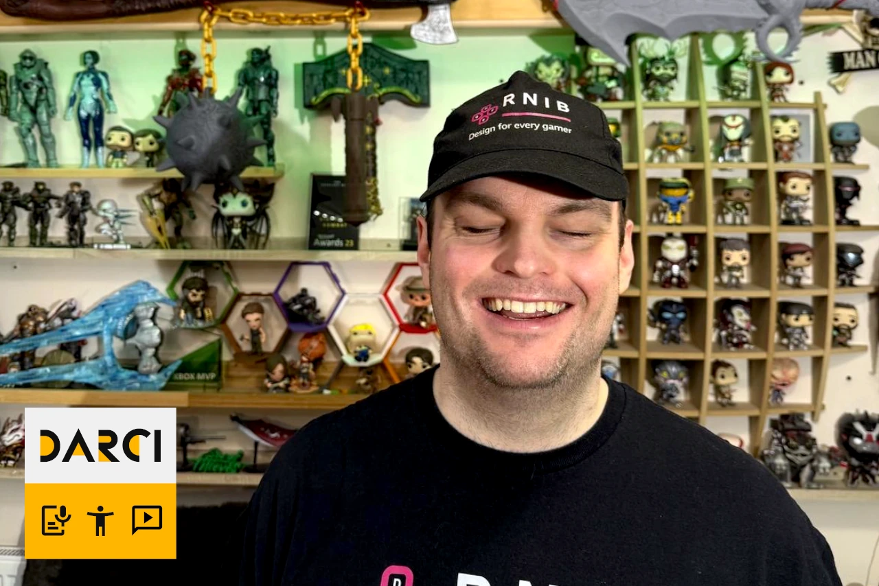 SK wearing a hat stands in front of shelves filled with action figures and gaming collectibles.